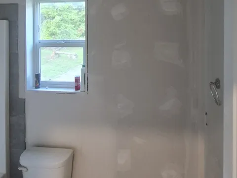 After: Same bathroom wall with new drywall hung and taped around the window