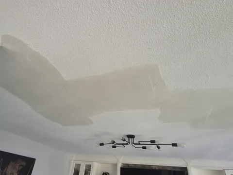 Before: Living room ceiling with large smooth drywall patches cut into the stipple texture